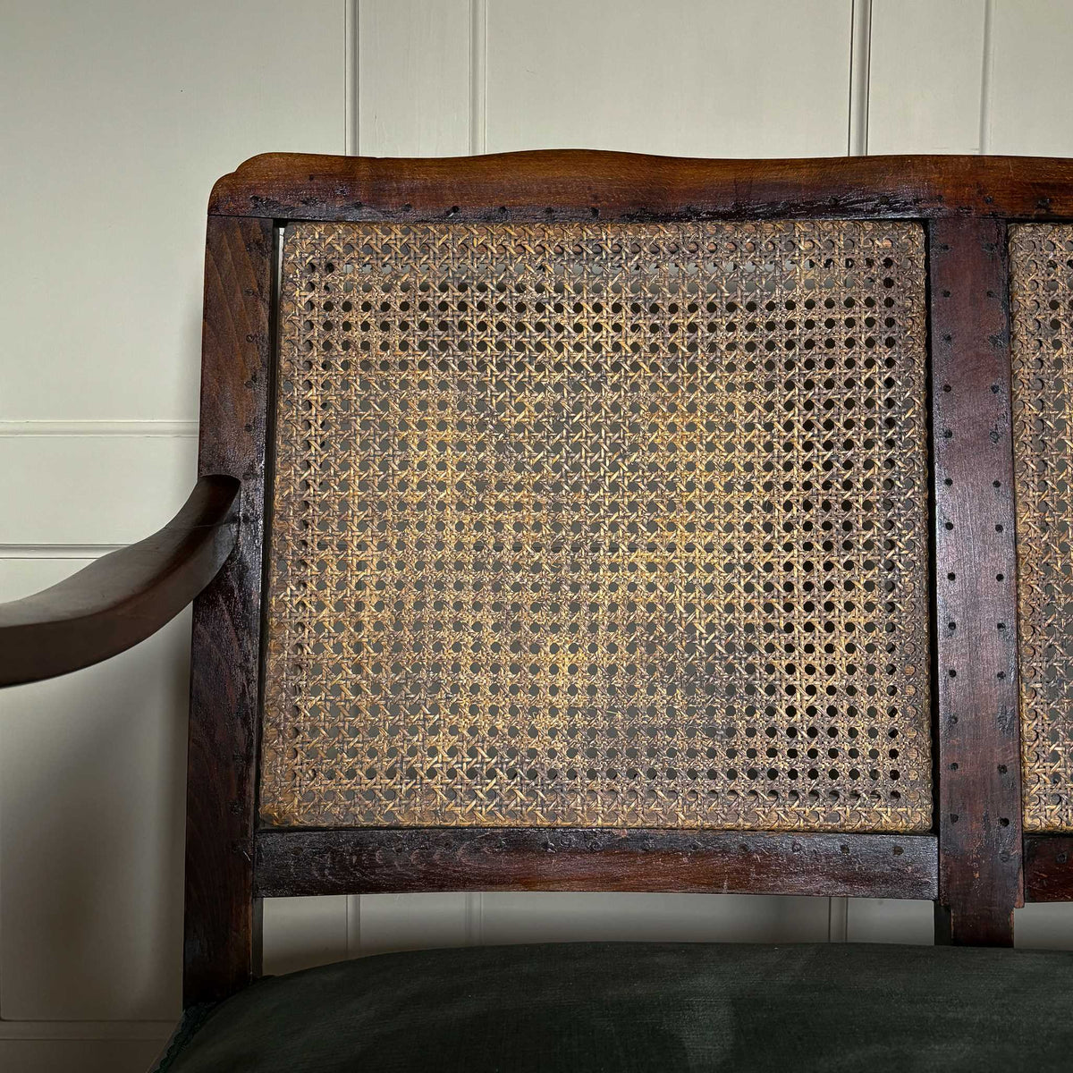 Close up detail of left side of cane backed vintage settee by Summerfield & Scott